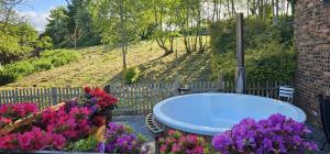 a bath tub in a garden with flowers at Owl's Watch in Ruthin