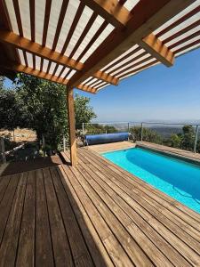 a wooden deck with a swimming pool and a pergola at Red and White אדום לבן in Amirim