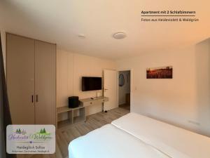 a hotel room with a bed and a tv at Heideglück Soltau - Ferienwohnungen An der Weide in Soltau