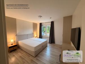 a bedroom with a white bed and a window at Heideglück Soltau - Ferienwohnungen An der Weide in Soltau