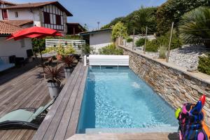 a swimming pool in a backyard with a wooden deck at MAISON GANTTIPIENEA in Ahetze