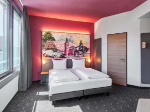 a bedroom with a bed with a painting on the wall at B&B HOTEL Rüsselsheim in Rüsselsheim