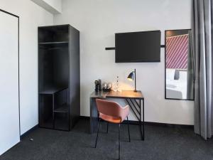 a room with a desk with a chair and a tv at B&B HOTEL Rüsselsheim in Rüsselsheim