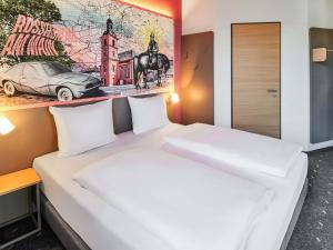 a large white bed in a room with a painting on the wall at B&B HOTEL Rüsselsheim in Rüsselsheim +20 photos