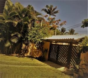 a wooden gate to a house with palm trees at Pousada Paraíso de Itaúna in Saquarema