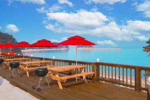 a deck with tables and red umbrellas on the beach at Nuhrang Nahrang in Taean