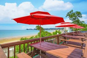 a row of picnic tables with red umbrellas at a beach at Nuhrang Nahrang in Taean
