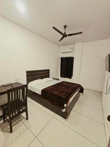 a bedroom with a bed and a desk and a ceiling fan at Thekkady Nest Residency in Thekkady