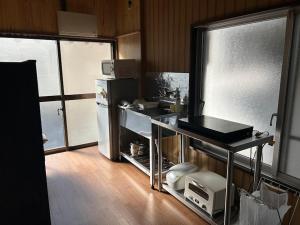 a kitchen with a refrigerator and a sink and a counter at YADOease in Tsuiki