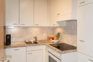 a kitchen with white cabinets and a sink at Edelweiss in Arosa