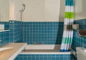 a blue tiled bathroom with a tub and a sink at Edelweiss in Arosa +4 photos