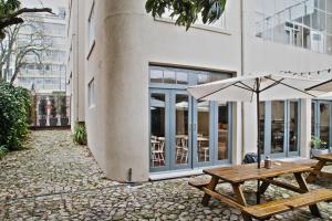 2 mesas de madera y sombrillas frente a un edificio en Porto Spot Hostel, en Oporto