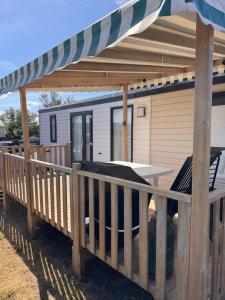 a deck with a table and an awning at mobil home spacieux climatisé sur camping sol a gogo in Saint-Hilaire-de-Riez