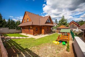 a wooden house with a playground in the yard at Drevenica Horehronka in Závadka nad Hronom