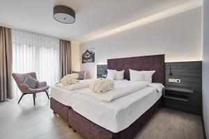 a hotel room with two beds and a chair at Hotel Ritter Badenweiler in Badenweiler