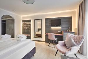 a hotel room with a bed and a desk and a tv at Hotel Ritter Badenweiler in Badenweiler