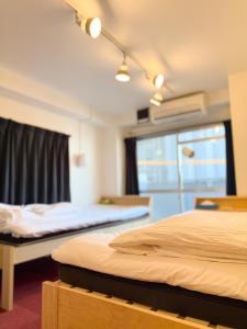 a hotel room with two beds and a window at GuestHouse Hostel MangeTak ゲストハウス マングタック広島 in Hiroshima