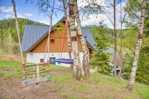 a log cabin with a swing in front of a house at Chalupy Bret v Krkonoších- prostorná chalupa se 3 apartmány, se saunou nebo vířivkou in Žacléř