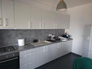 a kitchen with white cabinets and a sink and a stove at Marcus Residence Apartment in Satu Mare