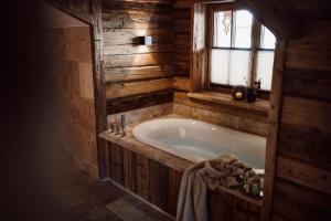 a bath tub in a wooden bathroom with a window at Chaletdorf Auszeit in Hüttschlag +28 photos