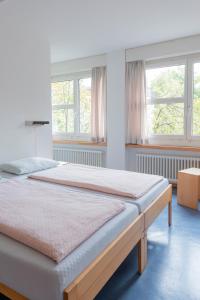 a large bed in a room with two windows at Zurich Youth Hostel in Zurich