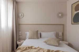 a bed with white sheets and pillows in a bedroom at Líbere Alicante Rambla in Alicante