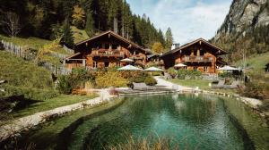 a lodge in the mountains with a pool of water at Chaletdorf Auszeit in Hüttschlag