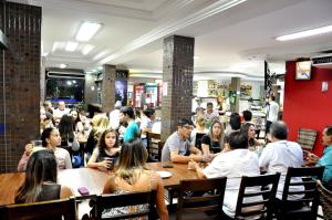 a group of people sitting at tables in a restaurant at Veneza Plaza Hotel in Gurupi