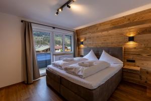 a bedroom with a large bed with a wooden wall at Alpen Lodge Kirchberg in Kirchberg in Tirol