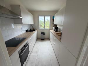 a kitchen with white cabinets and a window at La Bretonne vue mer in Lanmodez