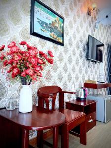 a room with a table with a vase of red roses at Yen Phu Hotel Tuy Hòa in Tuy Hoa