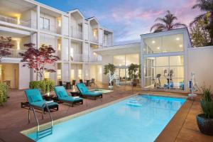 a swimming pool with blue chairs next to a building at Corporate Inn Sunnyvale - All-Suite Hotel in Sunnyvale