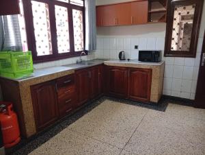 a kitchen with wooden cabinets and a sink and windows at Spring homes2 in Jinja