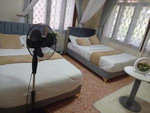 a room with two beds and a fan on a table at Spring homes2 in Jinja