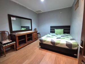 a bedroom with a bed and a vanity and a mirror at Maninjau House in Jakarta