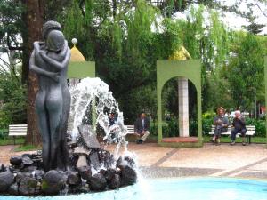 Una estatua de una mujer sentada junto a una fuente. en Hotel San Pietro, en Pato Branco