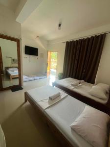 two beds in a room with a mirror and a window at Sapayag Backpacker's Inn in Dipolog