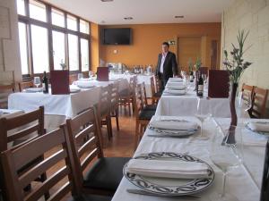 un hombre de traje parado en un restaurante con mesas en O Curruncho dos Lopez, en Mazaricos