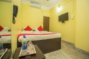 a hotel room with two beds and a television at Hotel O Kshounish Residency in Mālda