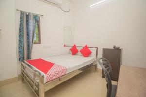 a small bed with red pillows in a room at Hotel O Kshounish Residency in Mālda