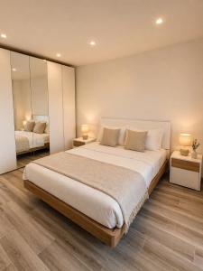 a bedroom with a large bed with two lamps and mirrors at Lake View Apartament 39 - Free Parking & Terrace in Cadegliano Viconago +8 photos