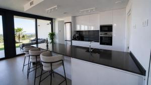 a kitchen with a black counter top and stools at Villa Kala in Polop