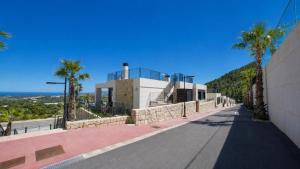 a road in front of a building with palm trees at Villa Kala in Polop