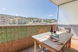 a wooden table with a bottle of wine on a balcony at "U Valincu" – Studio Centre Plage | by Efficios in Propriano