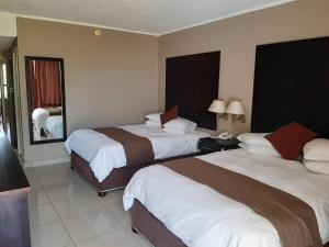 a hotel room with two beds and a mirror at Wilderness Beach Hotel in Wilderness