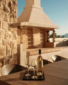 a bottle of wine sitting on a table with two glasses at Tomas Villas in Paleros