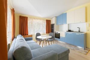 a living room with a blue couch and a kitchen at Къща за гости Бонев in Devin