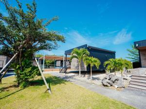 a house with palm trees in a yard at ＨＯＴＥＬ ＬＯＣＡＬ ＢＡＳＥ＜宮古島＞ in Miyako-jima