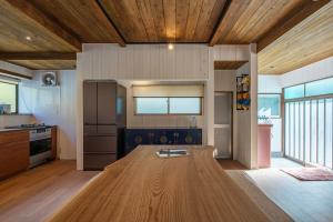 a kitchen with a wooden table in the middle of a room at Sotoura Sunrise Cottage 30m from Beach in Shimoda +26 photos