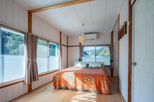 a bedroom with a bed in a room with windows at Sotoura Sunrise Cottage 30m from Beach in Shimoda